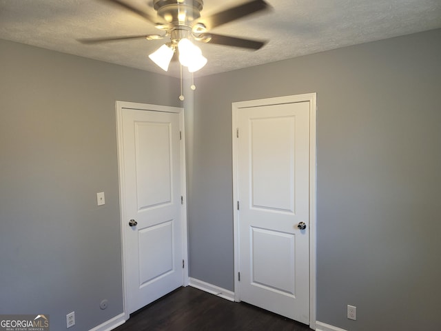 unfurnished bedroom featuring ceiling fan, dark hardwood / wood-style flooring, and a textured ceiling