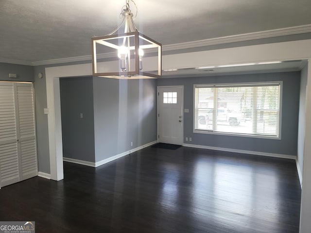 entryway with ornamental molding, dark wood-type flooring, and an inviting chandelier