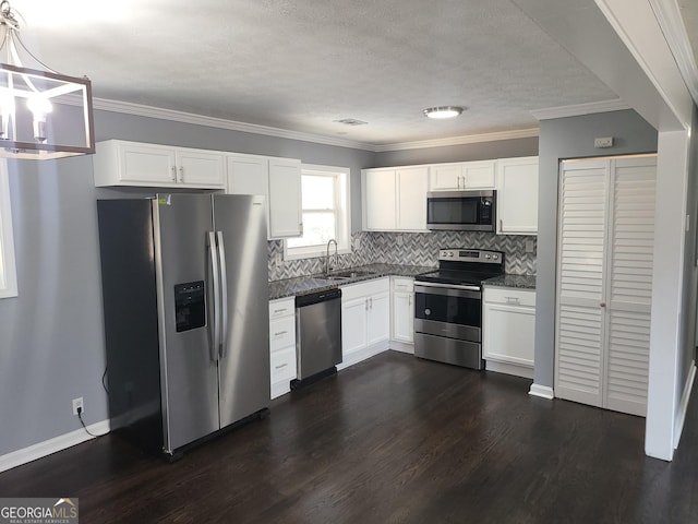 kitchen with sink, appliances with stainless steel finishes, white cabinetry, backsplash, and decorative light fixtures