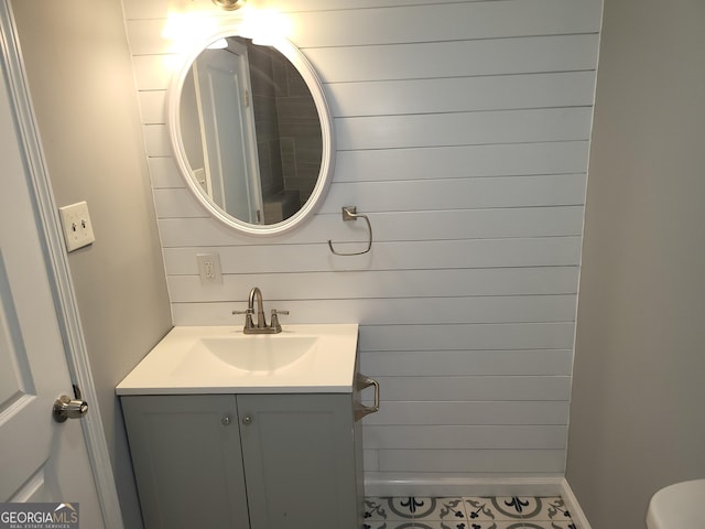 bathroom with tile patterned flooring, vanity, and wooden walls