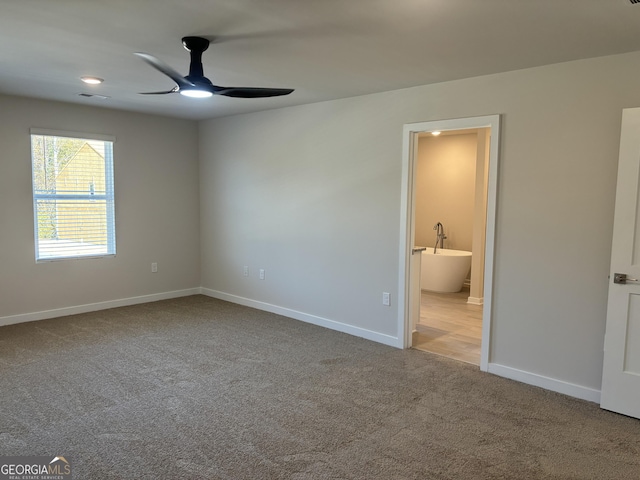 unfurnished bedroom featuring connected bathroom, light colored carpet, and ceiling fan