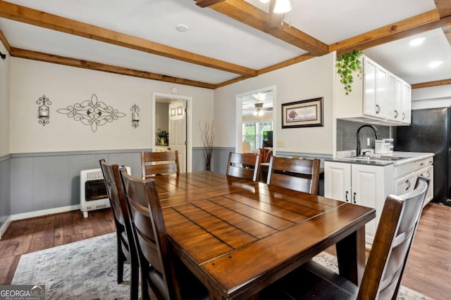 dining area featuring sink, ceiling fan, hardwood / wood-style floors, heating unit, and beamed ceiling