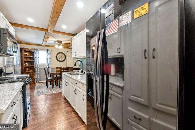 kitchen with beamed ceiling, white cabinetry, sink, and black appliances