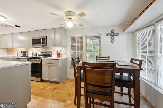 kitchen featuring stainless steel appliances, tasteful backsplash, gray cabinets, and ceiling fan