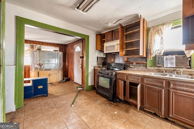 kitchen with black gas range oven, sink, light tile patterned floors, and a healthy amount of sunlight