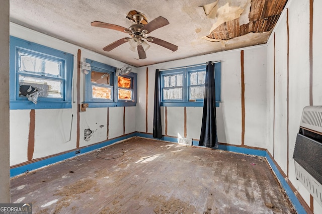 spare room with ceiling fan, heating unit, and a wealth of natural light