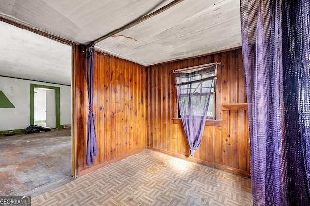 empty room featuring light parquet floors and wooden walls