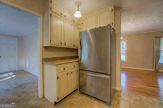 kitchen featuring stainless steel refrigerator, crown molding, hanging light fixtures, and a textured ceiling