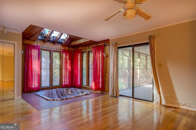 foyer entrance with crown molding, ceiling fan, hardwood / wood-style flooring, and vaulted ceiling with skylight