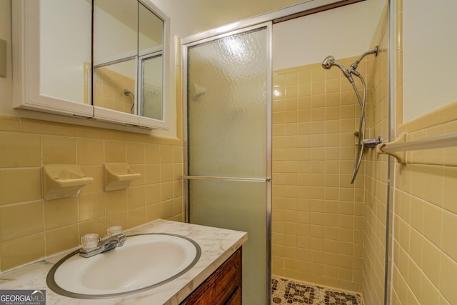 bathroom featuring vanity, a shower with shower door, and tile walls