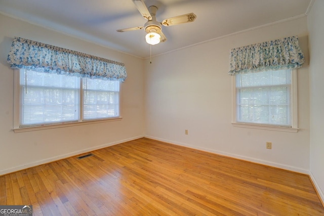 empty room with ceiling fan, wood-type flooring, and plenty of natural light