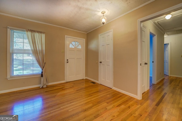 foyer entrance with crown molding, light hardwood / wood-style flooring, and a textured ceiling