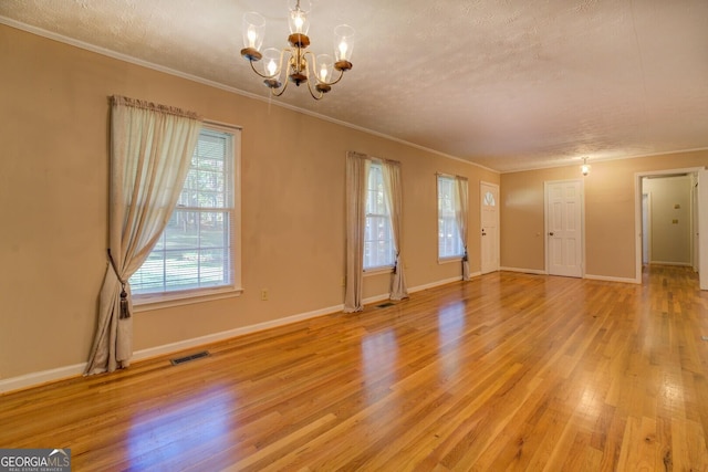 unfurnished room with a healthy amount of sunlight, a chandelier, a textured ceiling, and light hardwood / wood-style floors