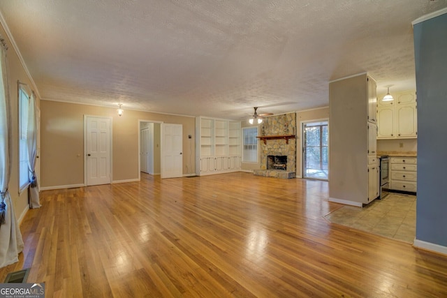 unfurnished living room with light wood-type flooring, a textured ceiling, a fireplace, and built in shelves