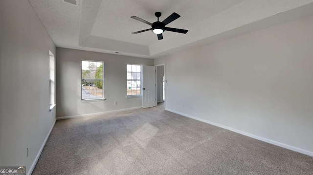 unfurnished room featuring light carpet, ceiling fan, a raised ceiling, and a textured ceiling