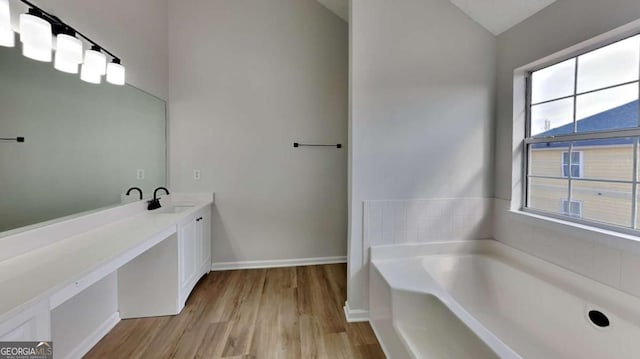 bathroom featuring wood-type flooring, lofted ceiling, a washtub, and vanity