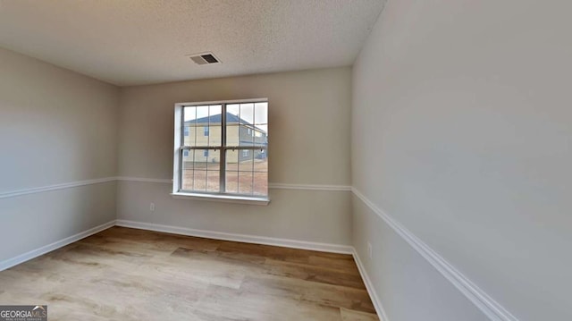 spare room featuring light hardwood / wood-style floors and a textured ceiling