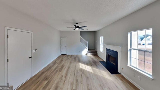 unfurnished living room featuring a textured ceiling, light hardwood / wood-style flooring, and ceiling fan