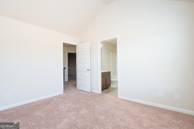 unfurnished bedroom with connected bathroom, vaulted ceiling, and light colored carpet