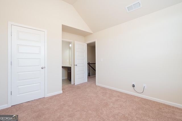 unfurnished bedroom with lofted ceiling, light colored carpet, and a closet