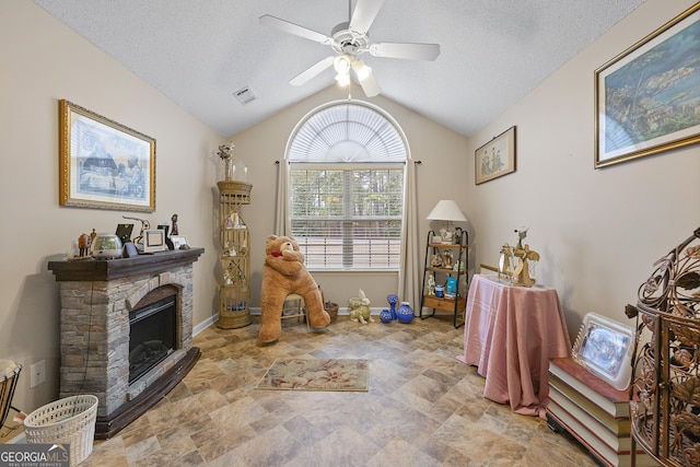 recreation room with a textured ceiling, a fireplace, ceiling fan, and vaulted ceiling