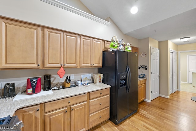 kitchen with vaulted ceiling, black fridge, and light hardwood / wood-style floors