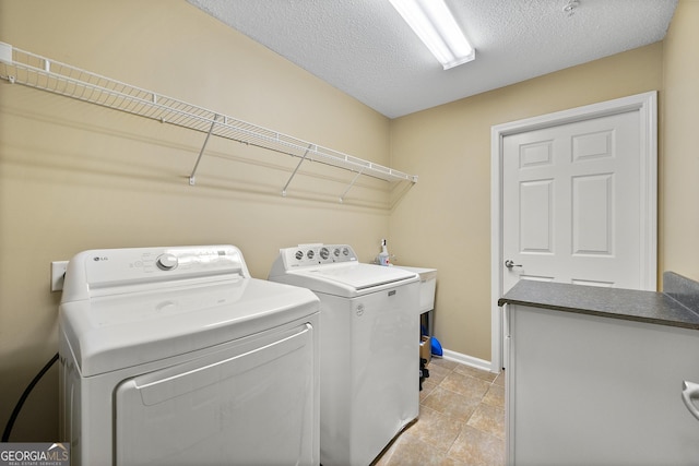 clothes washing area with washing machine and dryer and a textured ceiling