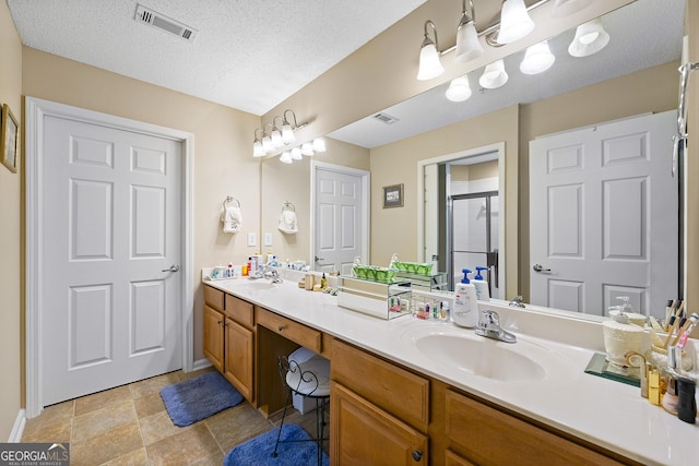 bathroom featuring vanity, a shower with door, and a textured ceiling