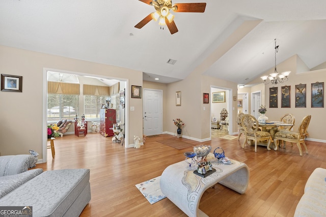 living room featuring lofted ceiling, ceiling fan with notable chandelier, and light hardwood / wood-style floors