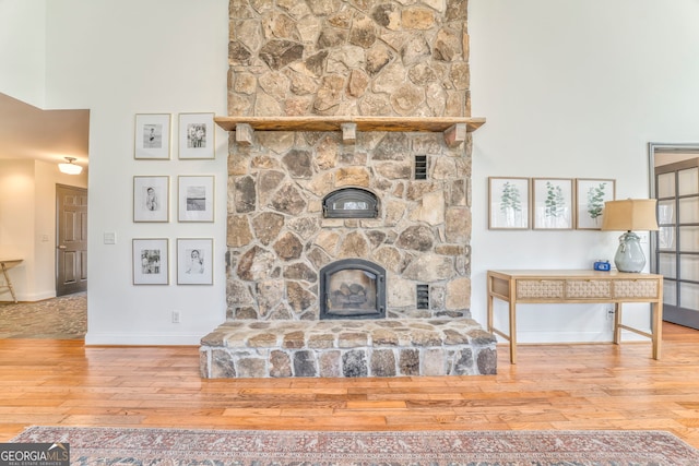 living room with hardwood / wood-style floors, a towering ceiling, and a fireplace