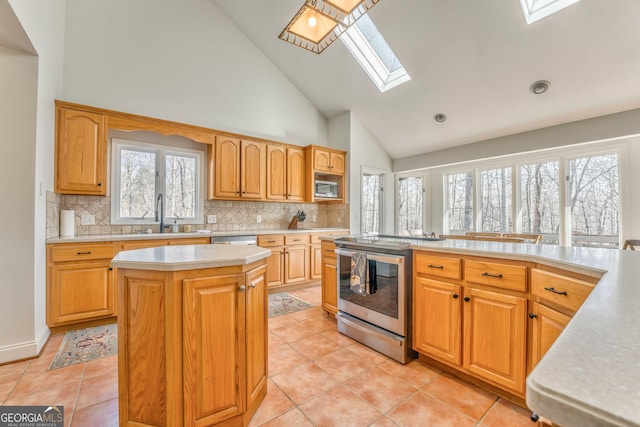 kitchen with sink, a skylight, a center island, appliances with stainless steel finishes, and backsplash