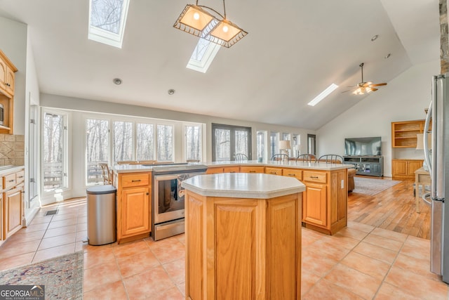 kitchen featuring hanging light fixtures, appliances with stainless steel finishes, a center island, and kitchen peninsula