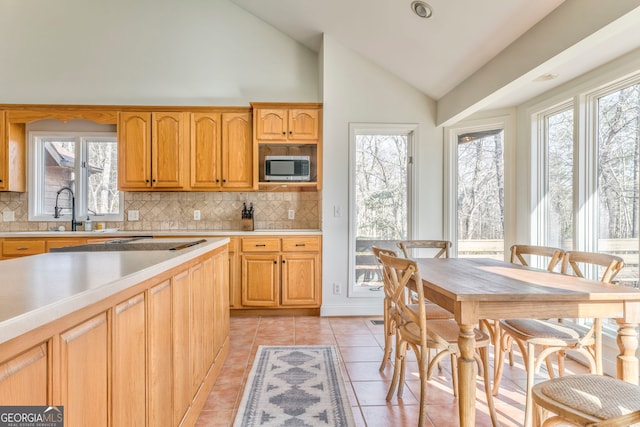 kitchen featuring lofted ceiling, sink, light tile patterned floors, and backsplash