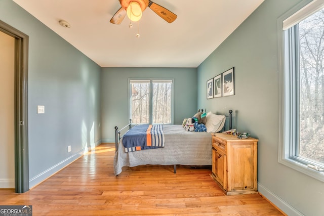 bedroom with ceiling fan, light hardwood / wood-style floors, and multiple windows