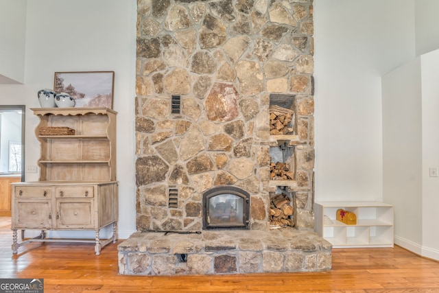 unfurnished living room featuring a stone fireplace and light hardwood / wood-style floors