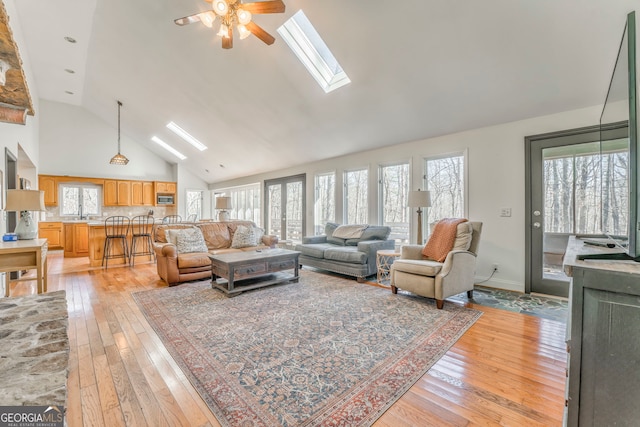 living room with light hardwood / wood-style flooring, high vaulted ceiling, and a skylight