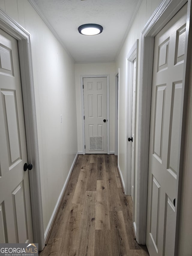 hall with ornamental molding and light hardwood / wood-style floors