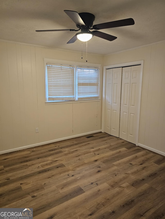 unfurnished bedroom with dark wood-type flooring, ceiling fan, and a closet