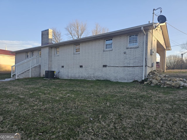 rear view of house featuring central AC unit and a yard