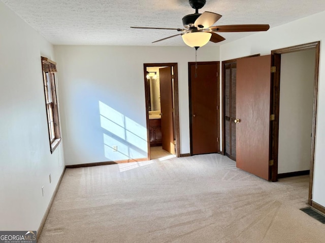 empty room featuring ceiling fan, light colored carpet, and a textured ceiling