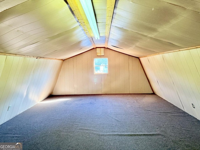 bonus room featuring vaulted ceiling, carpet flooring, and wooden walls