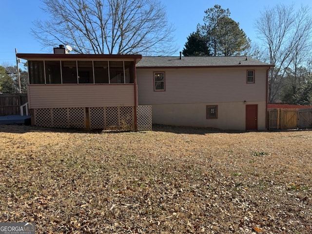 back of property with a yard and a sunroom