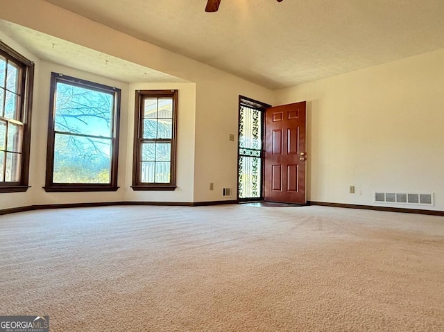 carpeted spare room with a wealth of natural light and ceiling fan