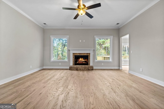 unfurnished living room featuring crown molding, ceiling fan, a brick fireplace, and light hardwood / wood-style flooring