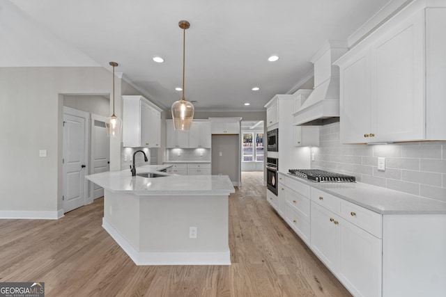 kitchen with premium range hood, appliances with stainless steel finishes, decorative light fixtures, sink, and backsplash