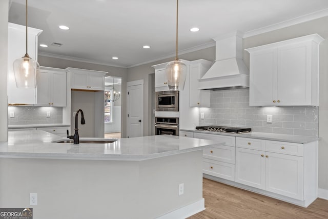 kitchen with white cabinetry, decorative light fixtures, stainless steel appliances, and premium range hood