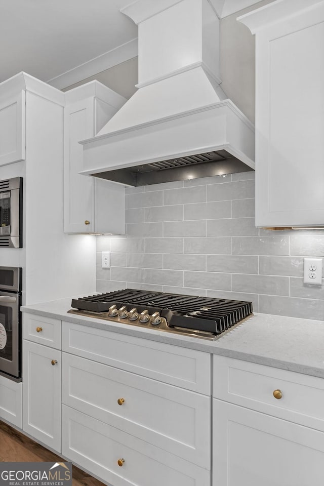 kitchen with white cabinetry, backsplash, custom exhaust hood, and stainless steel appliances