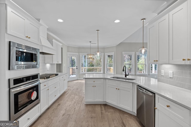 kitchen featuring appliances with stainless steel finishes, tasteful backsplash, sink, white cabinets, and hanging light fixtures