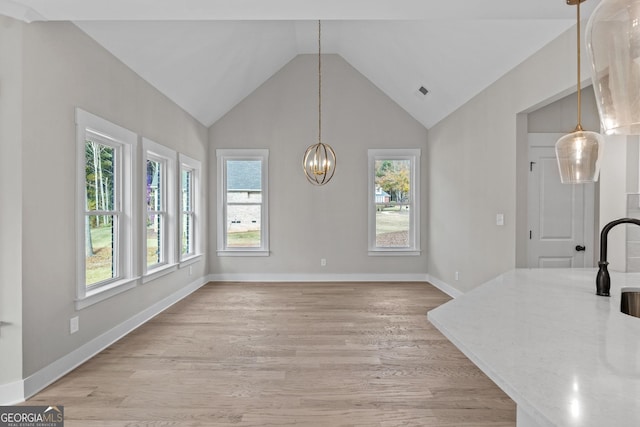 dining area with vaulted ceiling, a chandelier, and light hardwood / wood-style floors