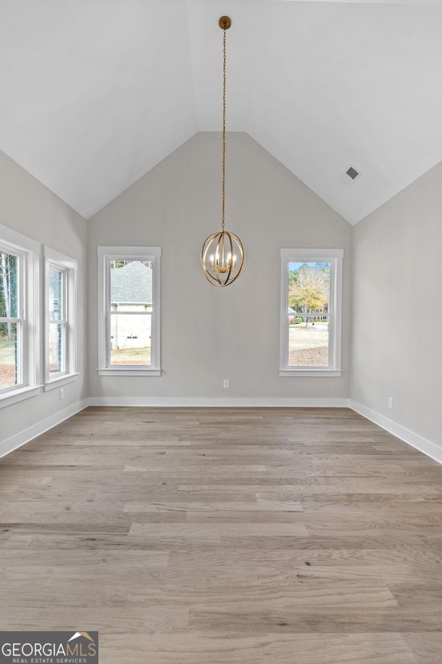 unfurnished dining area with a notable chandelier, light hardwood / wood-style flooring, and vaulted ceiling